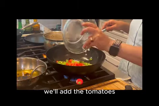 Tomatoes being added to green peas in a wok