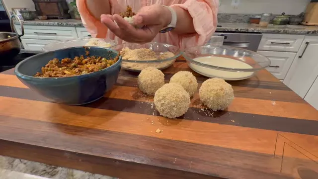 Hands placing spiced vegan keema filling inside a rice wrapper beside breadcrumbs and plant milk