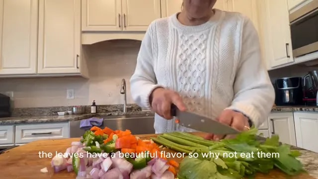 Chopped shallots, carrots, peppers, garlic, and celery on a wooden cutting board