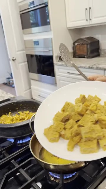 White plate holding chopped steamed wheat gluten pieces beside a pan