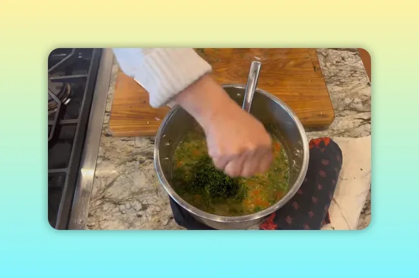 Hand squeezing lemon over pea soup topped with chopped green herbs