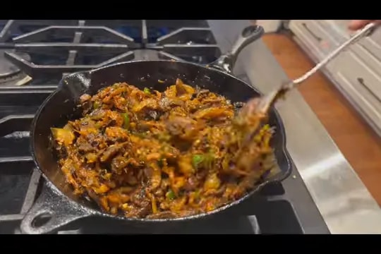 Dark mushroom and pepper filling being stirred in a cast iron skillet