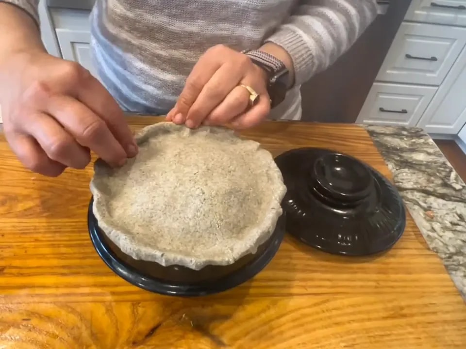 Thick dough covering a black pot with its edges pressed onto the rim