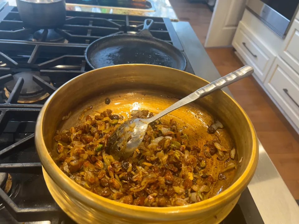 Browned onions mixed with raisins and nuts in a wide pan