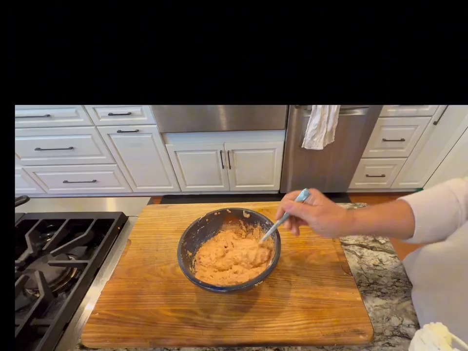 A spoon holding thick lentil batter above a mixing bowl